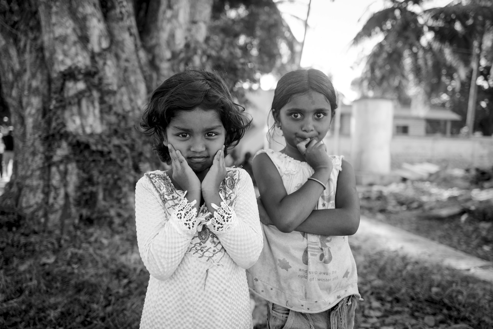 two young girls standing in front of a tree